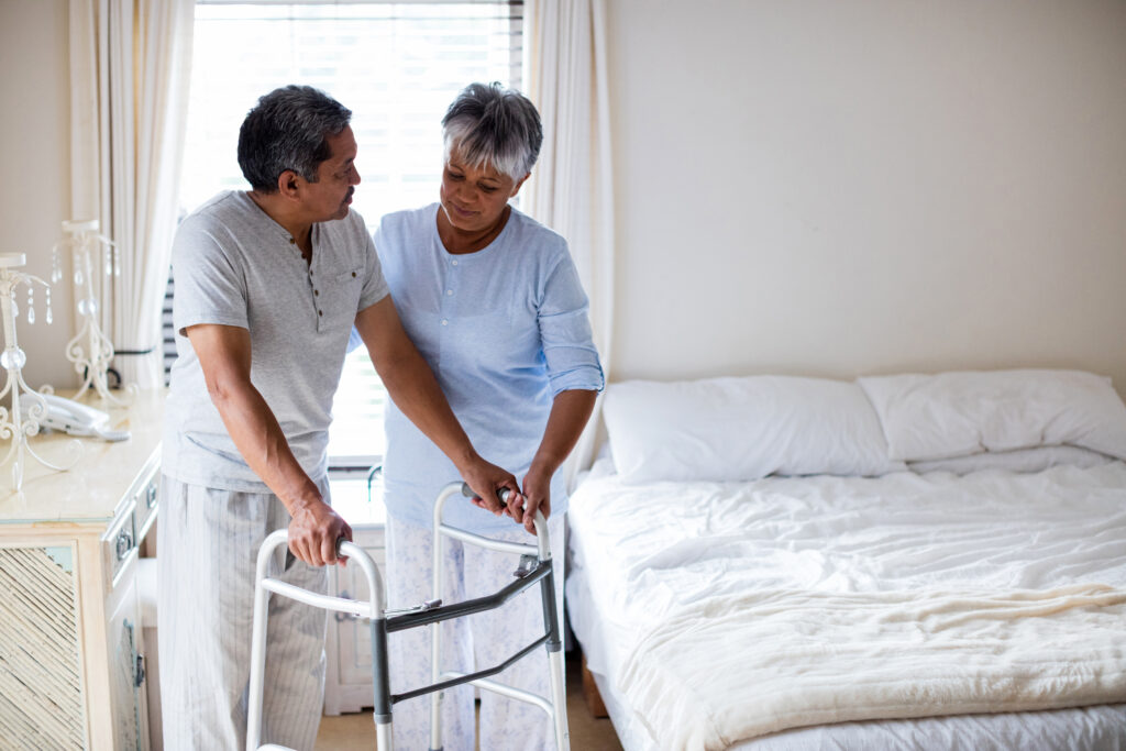 A woman providing family caregiving to her relative by assisting him from bed to his walker